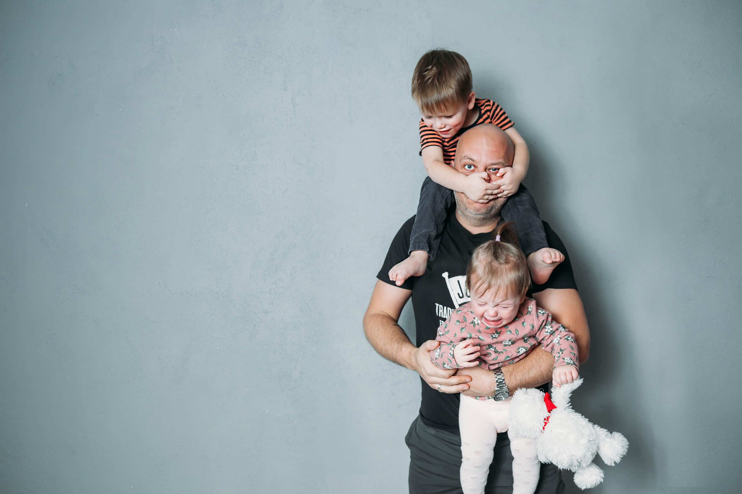 Vater mit zwei kleinen Kindern in einer stressigen Alltagssituation
